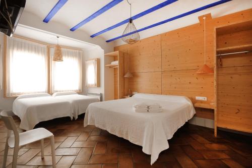 2 łóżka w pokoju z drewnianymi ścianami i niebieskimi belkami stropowymi w obiekcie B&B Sant Pol - Adults Only w mieście San Pol de Mar