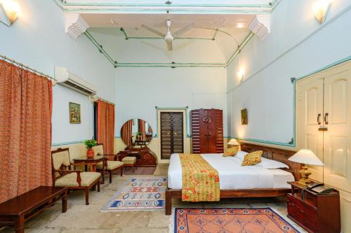 a bedroom with a bed and a chair and a table at Neemrana's - Piramal Haveli in Bagar