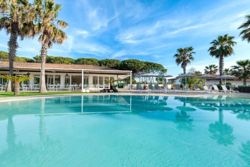 a large swimming pool in front of a building with palm trees at Paestum Inn Beach Resort in Paestum