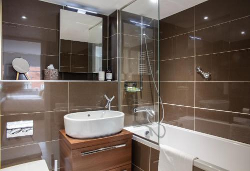 a bathroom with a sink and a mirror and a tub at Kensington High Street One Bed in London