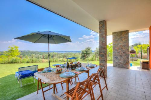 - une table en bois avec des chaises et un parasol sur la terrasse dans l'établissement Villa Teresa Apt Lake Garda View - Happy Rentals, à Soiano del Lago