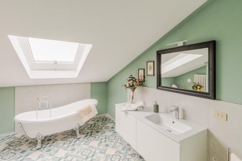 a bathroom with a tub and a sink and a mirror at Cà Uvenere, Modern Farmhouse with Pool in Montecalvoli