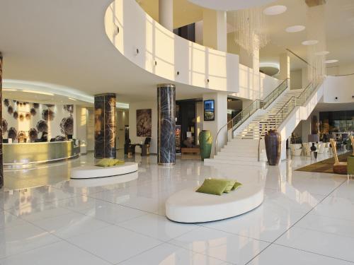 a large lobby with two white ottomans in a building at Melia Braga Hotel & Spa in Braga