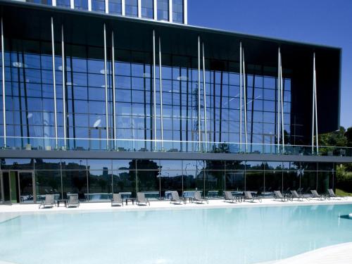 a building with chairs and a pool in front of it at Melia Braga Hotel & Spa in Braga