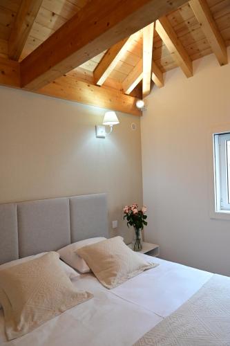 um quarto com uma cama com lençóis brancos e tectos em madeira em Casa do Pó, Alojamento Local em Lamego