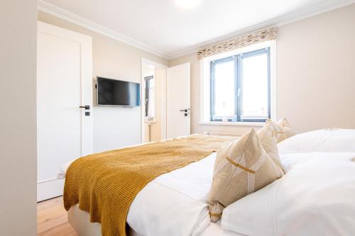 ein weißes Schlafzimmer mit einem Bett und einem Fenster in der Unterkunft Stadthaus Boysen Whg 7 in Westerland