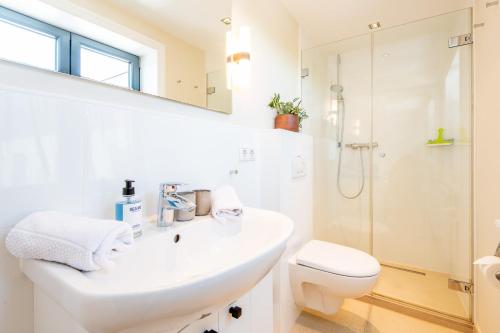ein weißes Bad mit einem Waschbecken und einer Dusche in der Unterkunft Stadthaus Boysen Whg 7 in Westerland
