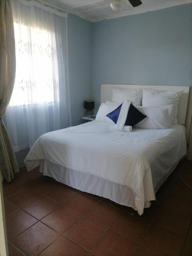 a bedroom with a white bed with pillows and a window at Best of Pearls Guesthouse in Empangeni
