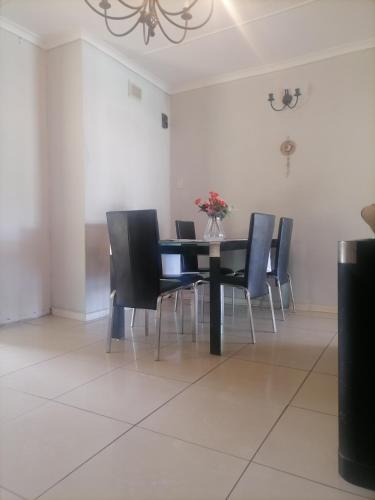 a dining room with a black table and chairs at Best of Pearls Guesthouse in Empangeni