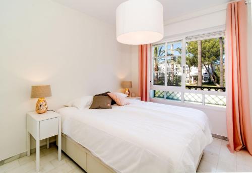 a bedroom with a white bed and a window at Tropical Getaway Townhouse in Nueva Andalucia close to Los Naranjos Golf in Marbella