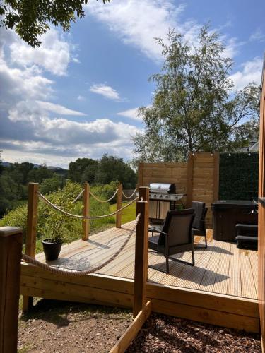 a wooden deck with a table and chairs on it at River Huts, Highland River Retreat with Hot Tub in Inverness