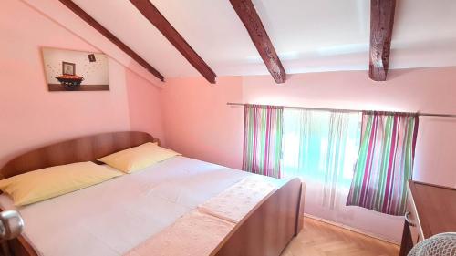 a small bedroom with a bed and a window at Apartments Ivetić in Kotor