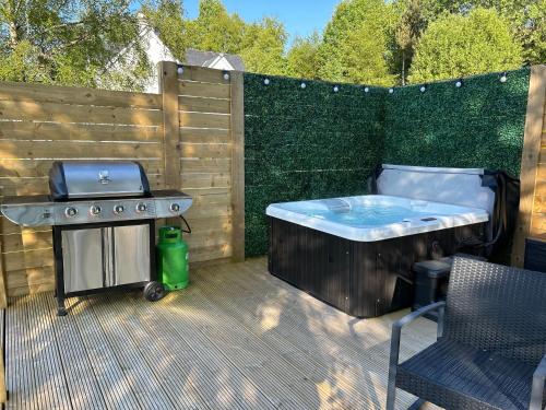 a hot tub and a grill on a patio at River Huts, Highland River Retreat with Hot Tub in Inverness