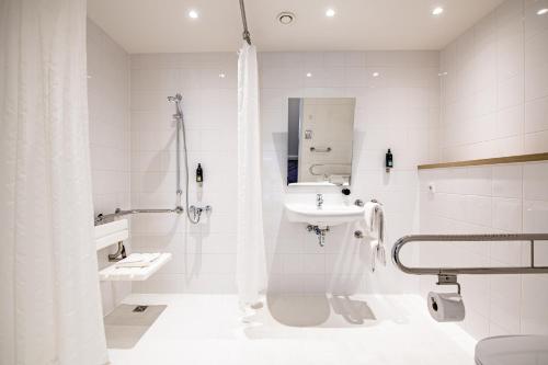 a white bathroom with a sink and a shower at Premier Inn München Messe in Haar