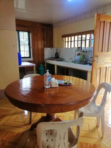 a kitchen with a wooden table and white chairs at Inn Maugay Bed and Bath in Sagada