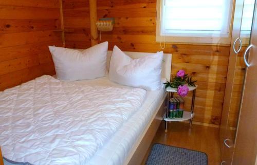 un letto con lenzuola e cuscini bianchi in una stanza di Bungalow "Heimliche Liebe" a Bansin