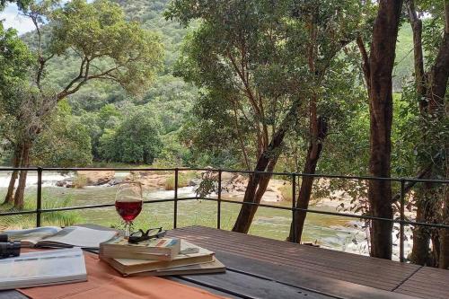Kampersrus AH的住宿－Riverfront View - House on Blyde，一张木桌,上面放着一杯葡萄酒和书籍