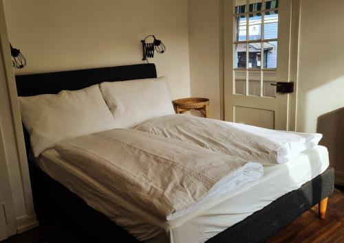 a bedroom with a bed with white sheets and a window at Swiss Holiday Apartments in Spiez