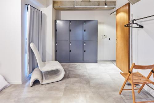 a room with a white chair and a closet at Tora Hotel Asakusa in Tokyo