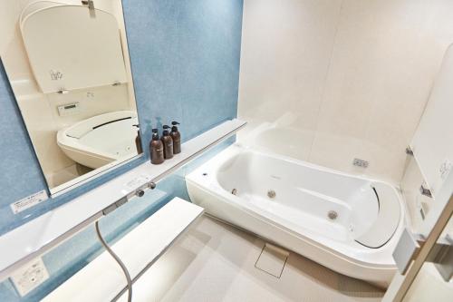 a bathroom with a tub and a toilet and a sink at Tora Hotel Asakusa in Tokyo