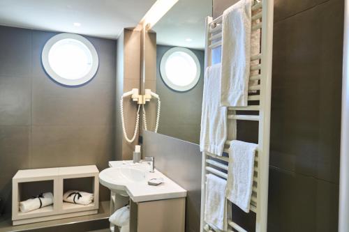 a bathroom with a sink and a toilet and two windows at Hotel Miramare in Marina di Varcaturo