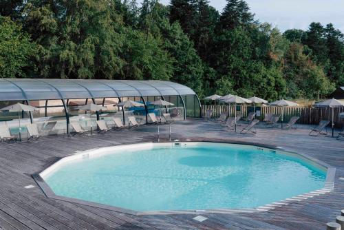 une grande piscine avec chaises et parasols dans l'établissement Huttopia Calvados - Normandie, à Moyaux
