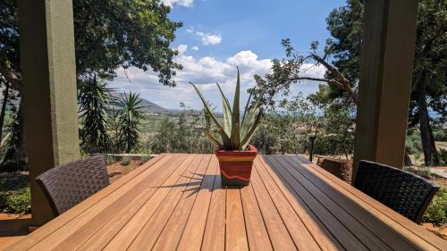 einem Holztisch mit Topfpflanze auf einer Veranda in der Unterkunft Villa Khaki 