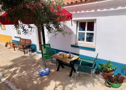 eine Terrasse mit einem Tisch, Stühlen und einem Baum in der Unterkunft Casa Anneli - relaxing under the olive tree in Aljezur