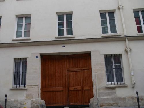 - un bâtiment blanc avec une porte et des fenêtres en bois dans l'établissement Appartement Quartier Latin 4 personnes, à Paris