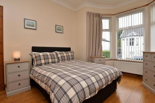 a bedroom with a bed with a plaid blanket and a window at Freeland Cottage in Dunoon