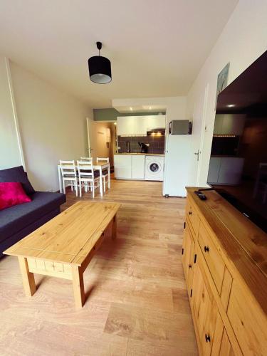 un salon avec un canapé et une table en bois dans l'établissement Calme et arborée proche de la plage, à Cabourg