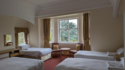 a hotel room with three beds and a window at Cober Hill in Scarborough