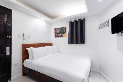 a white bedroom with a bed and a television at NEST NANO SUITES POBLACION-MAKATI in Manila