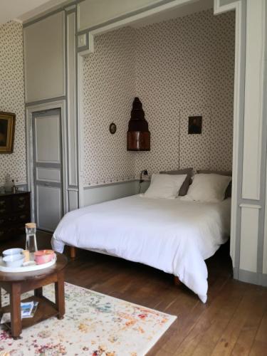 Un dormitorio con una gran cama blanca y una mesa en Le boudoir de Yaya en Cosne Cours sur Loire