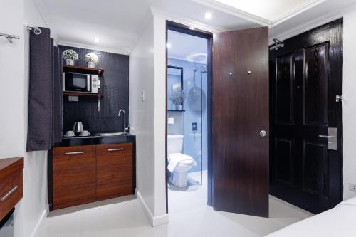 a bathroom with a sink and a toilet and a door at NEST NANO SUITES POBLACION-MAKATI in Manila