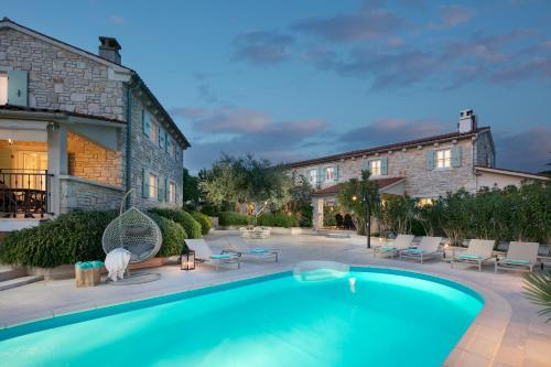 einen Pool in einem Garten mit Stühlen und einem Gebäude in der Unterkunft Residence Pietre d'Istria - with private service in Burići