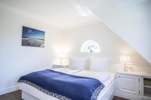 a white bedroom with a blue blanket on a bed at Haus-Twesk-Merre in Munkmarsch