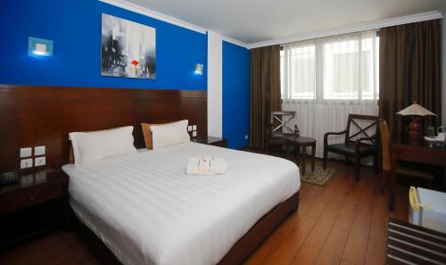 - une chambre avec un grand lit et un mur bleu dans l'établissement Central Hotel Tana, à Antananarivo