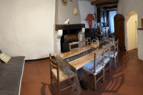 een eetkamer met een tafel en stoelen en een open haard bij maison à la campagne in Quinson
