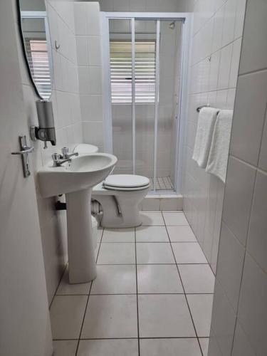 a white bathroom with a toilet and a sink at 20 Brandersig in Jeffreys Bay
