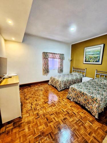 a hotel room with two beds and a wooden floor at Kulem Gempol in Bandung