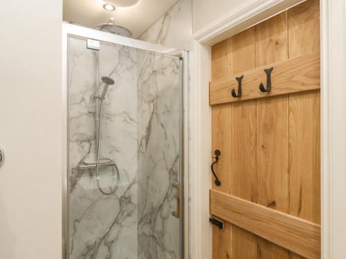 een douche met een glazen deur in een badkamer bij Bluefin Cottage in Whitby