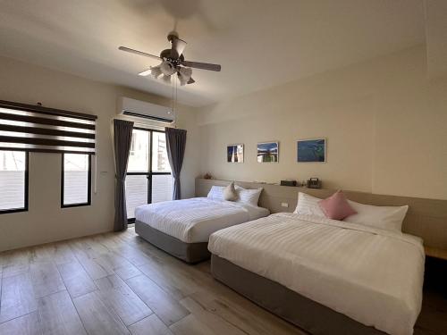 Un dormitorio con dos camas y un ventilador de techo. en 西衛左岸觀海民宿, en Ch'ao-yang