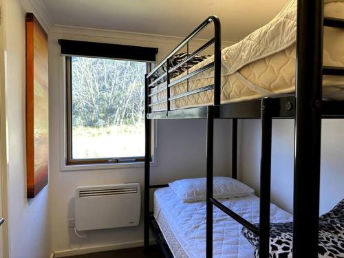a small room with a bunk bed and a window at Cape Cod Chalet, alpine-getaways in Dinner Plain