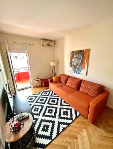 ein Wohnzimmer mit einem orangenen Sofa und einem Teppich in der Unterkunft Apartman Filip in Podgorica