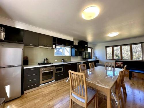 a kitchen with a dining table and a kitchen with a refrigerator at Cape Cod Chalet, alpine-getaways in Dinner Plain