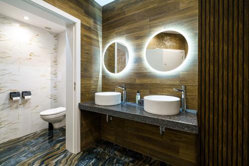 a bathroom with two sinks and a toilet and mirrors at Bistra & Galina Hotel in Ruse