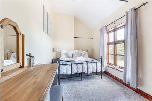 a bedroom with a bed and a mirror at Woodrow End Cottage in Cawston