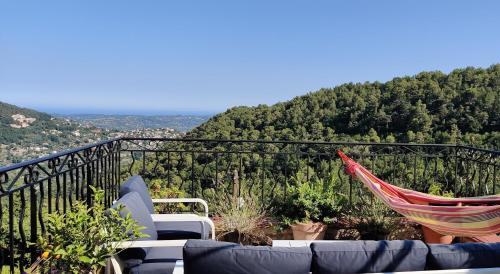 a hammock and chairs on a balcony with a mountain at Mas des Buscades in Cabris