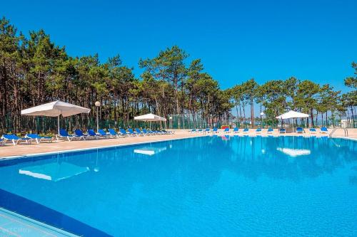 a large swimming pool with chairs and umbrellas at Kampaoh Vagueira in Palheiros da Vagueira